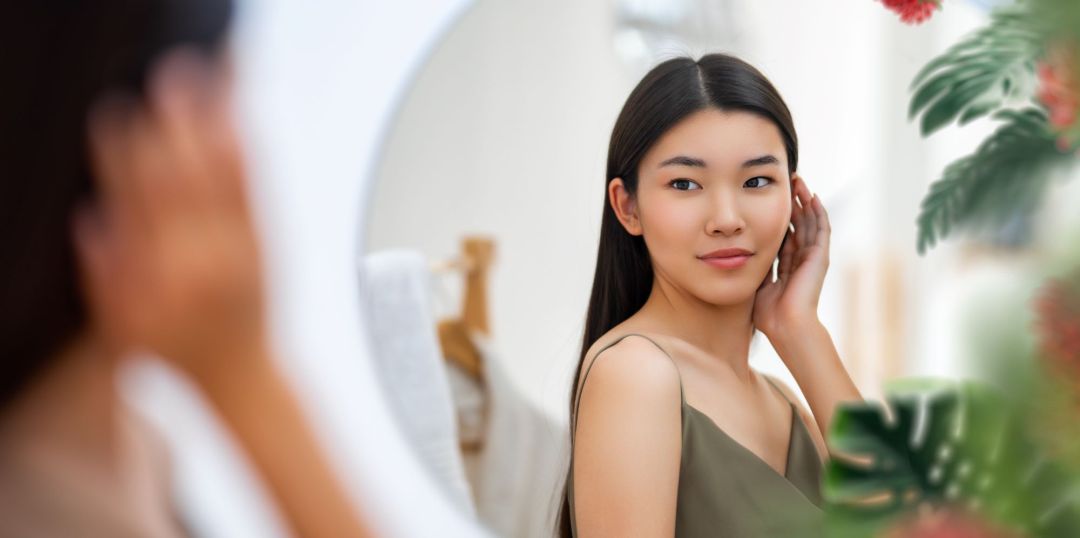 woman looking in mirror summer skincare routine