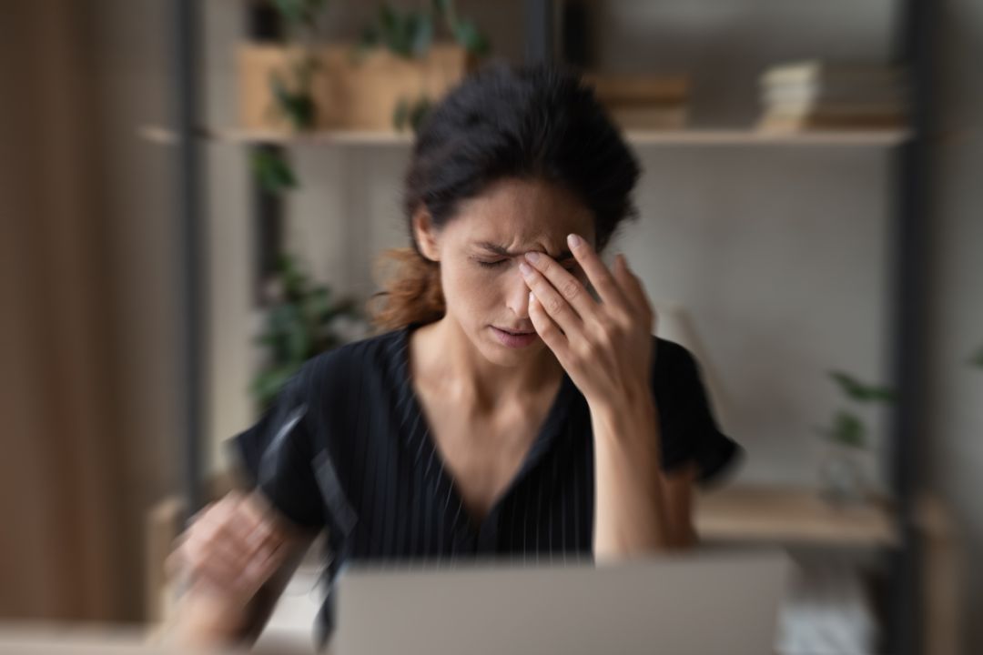 Woman sits rubbing head in front of computer, confused by artificial intelligence