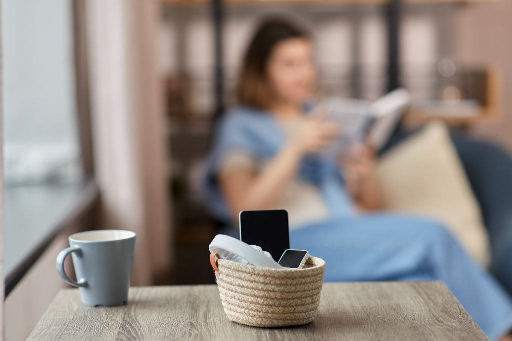 woman sits reading book, phone in basket. managing her digital wellbeing