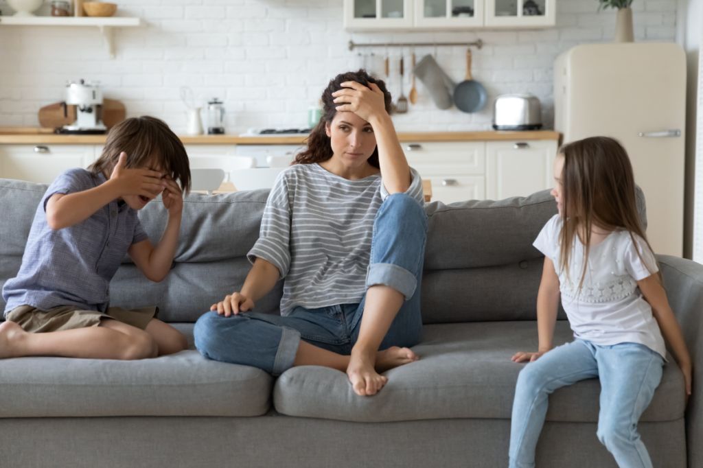 Tired mother sits between her arguing son and daughter