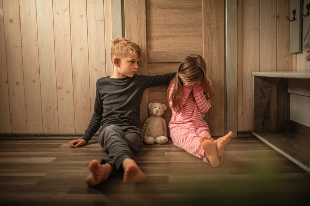 Brother shows kindness to sad little sister, patting her on the back