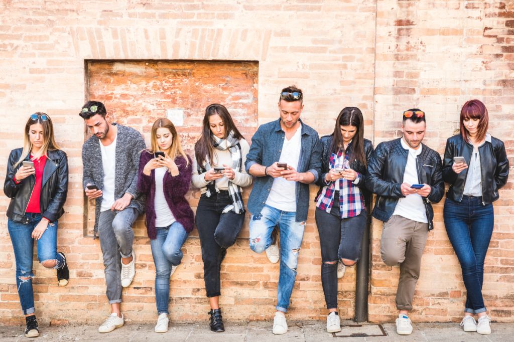 group of young people all lined p all using phones