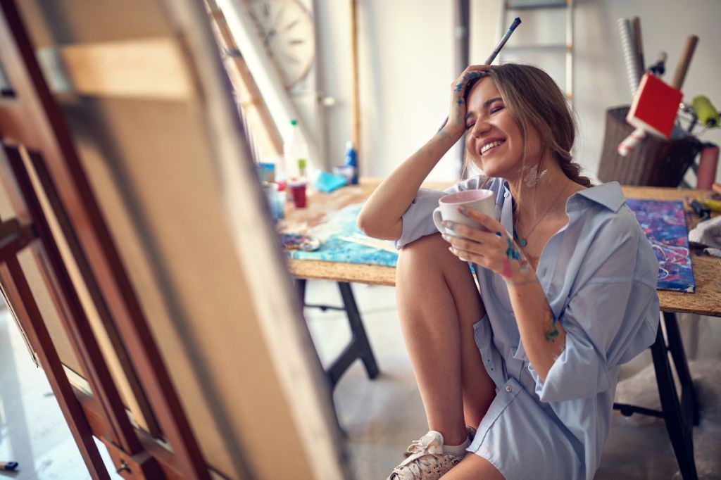 happy woman sits at easel