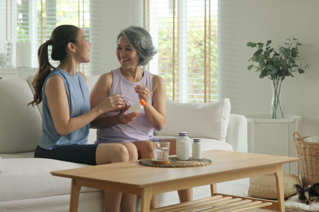 Young woman helps older woman with medicine