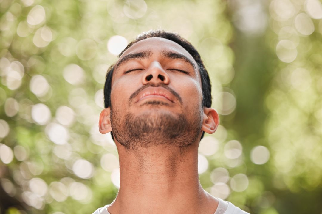 man takes deep breath in nature