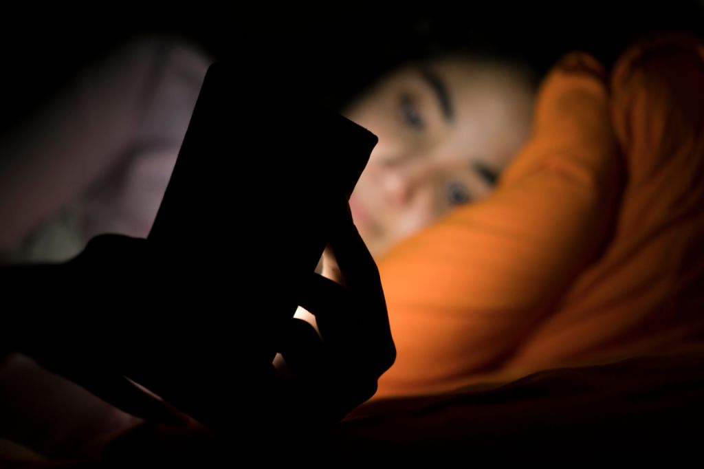 woman is using phone in bed, social media addiction
