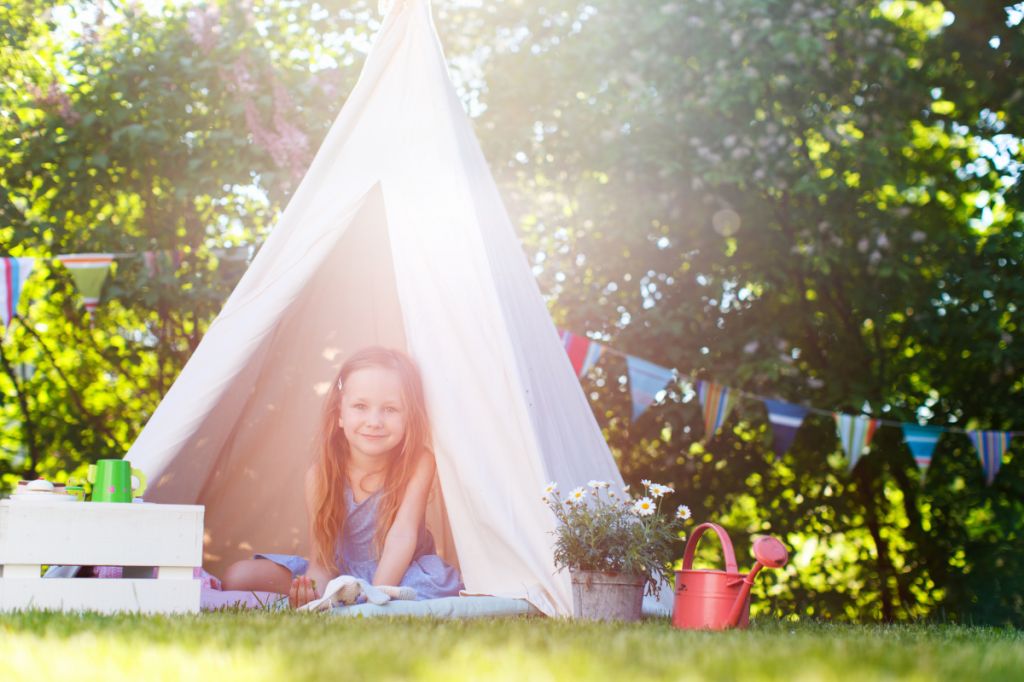 little girl playing in tent in garden