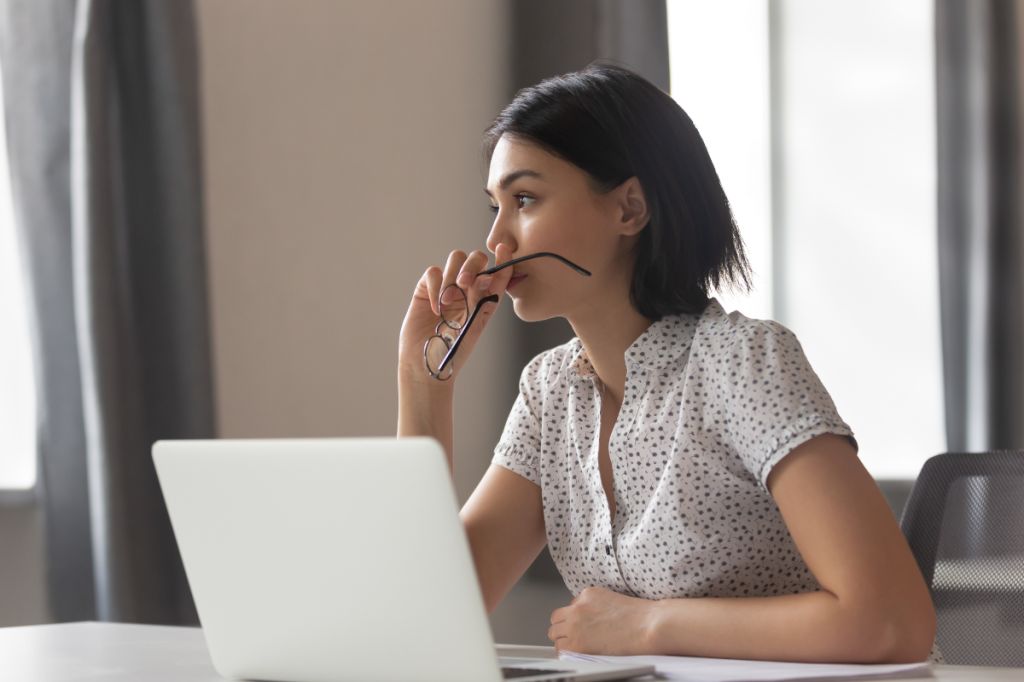 woman looks thoughtfully away from desk