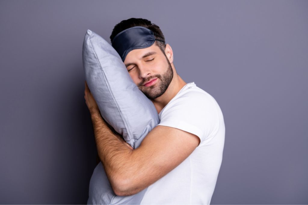 happy man relaxes with eye mask and pillow