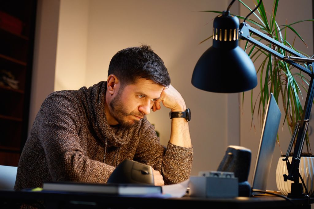 man looks tired and burnout staring at computer