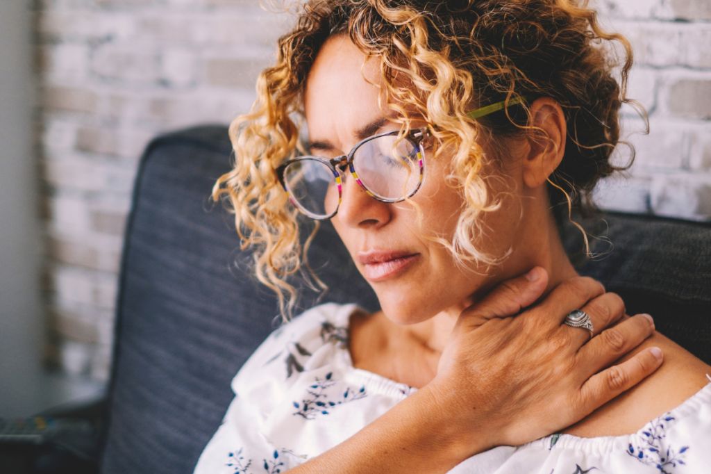 stressed woman rubs shoulder