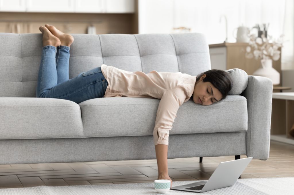 woman lying asleep on sofa when supposed to be on computer