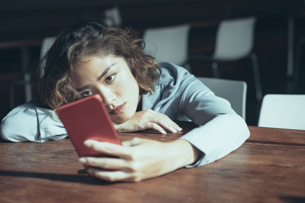 Woman looks at phone, worried about a message she has sent
