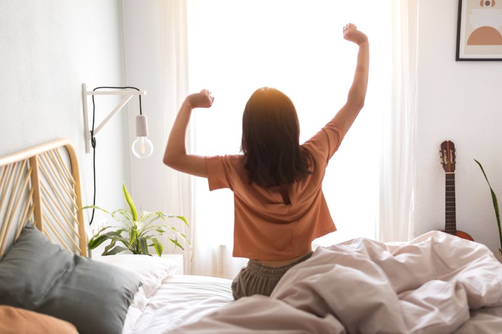 woman in nice bedroom stretches and gets ready to get up