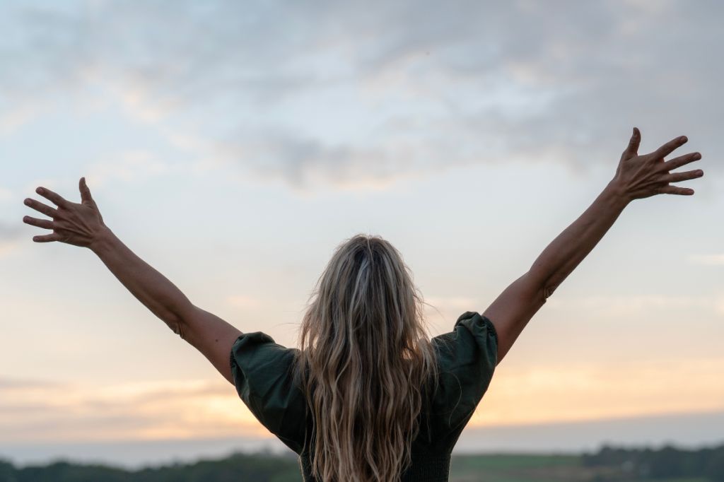 woman with arms spread up to sky