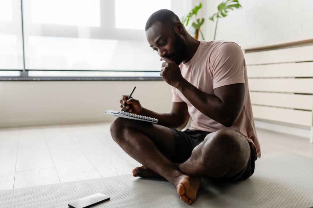 man writing in journal, tracking his feelings