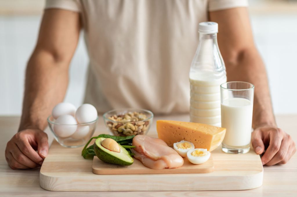 Man has huge tray of protein foods, with nuts, eggs, avocado, milk, chicken and cheese
