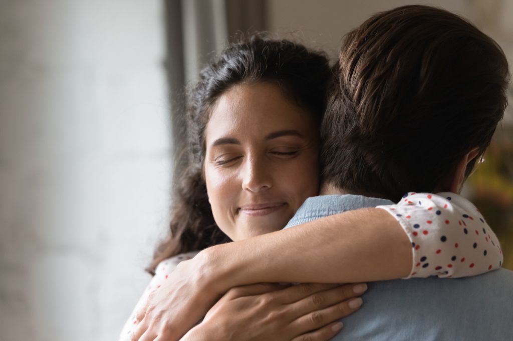 woman hugs man, looks happy after reconciliation