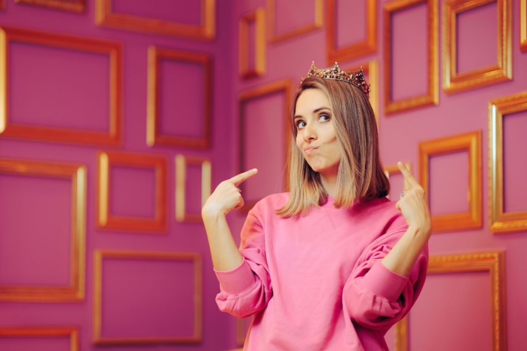 Vain woman wears crown and points to herself - overt narcissist