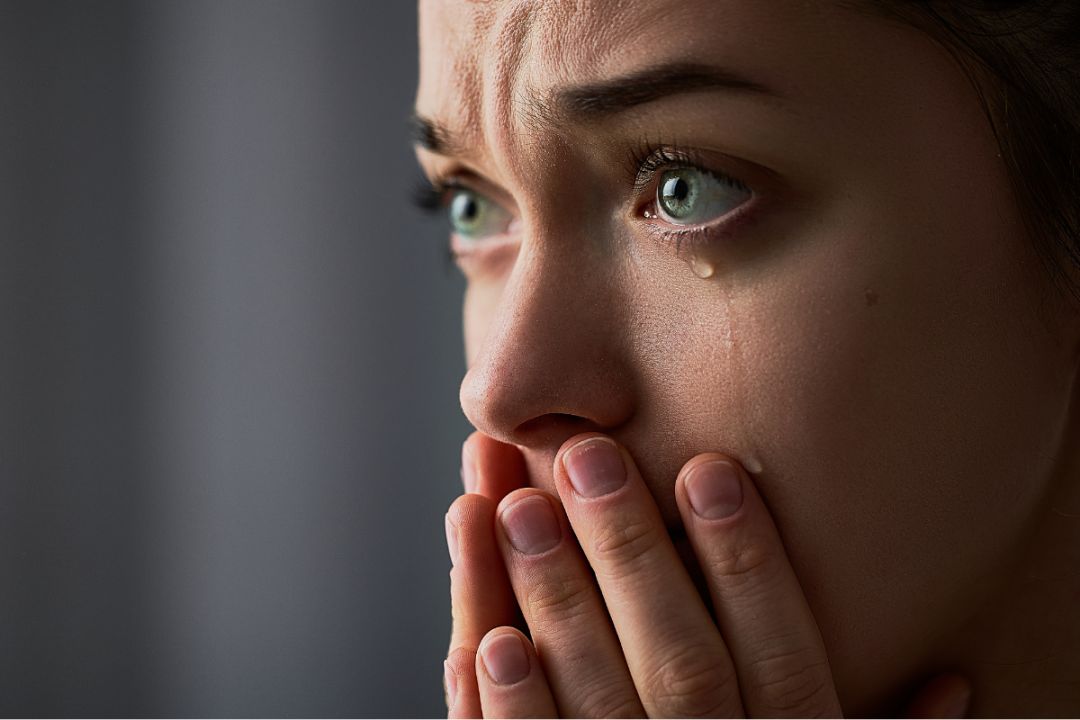 woman in tears, hands over mouth