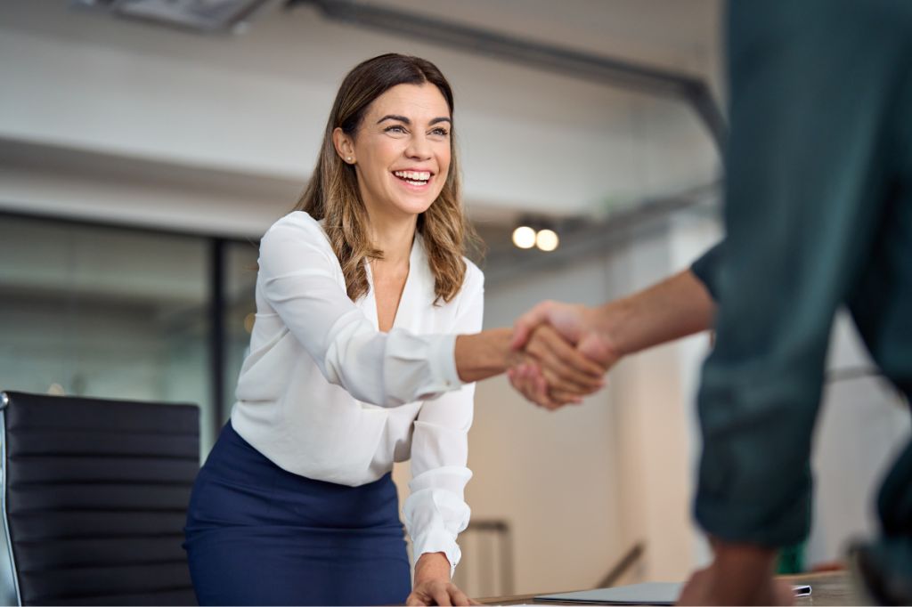 Confident woman smiles and shakes hands in thanks