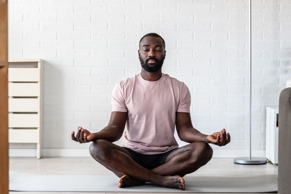 man sits in a cross-legged pose practising breathwork
