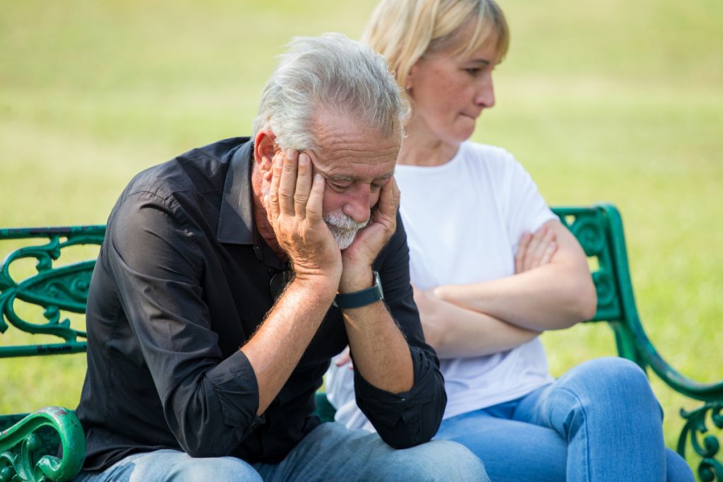 Man looks downhearted as woman sits pursed lips and looks away