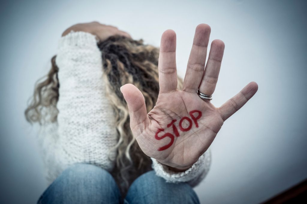 woman holds up hand with word stop written in red