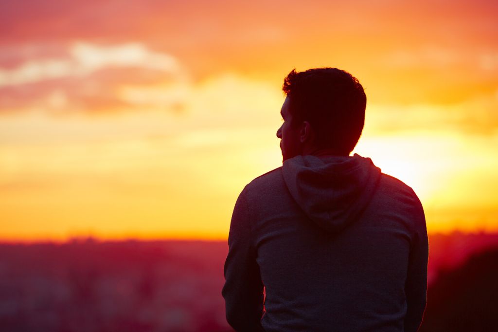 man relaxes alone at sunset