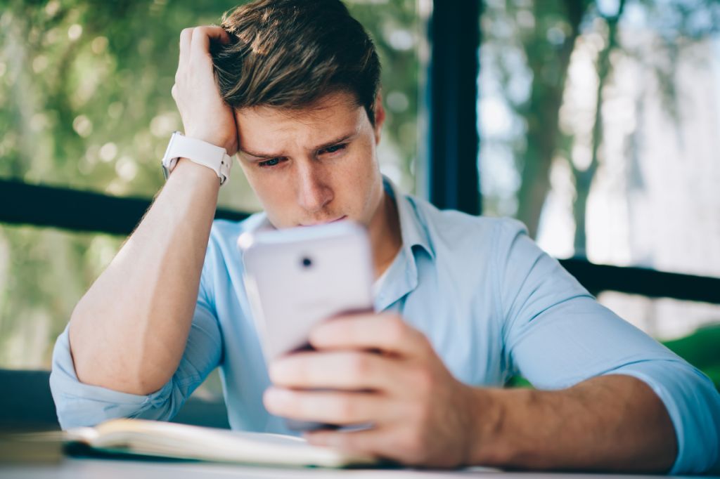 man looks at phone with tears in his eyes