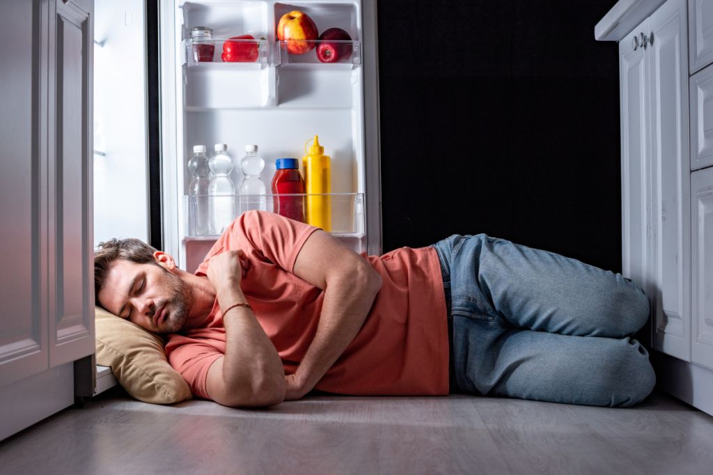 man sleeps with head in fridge