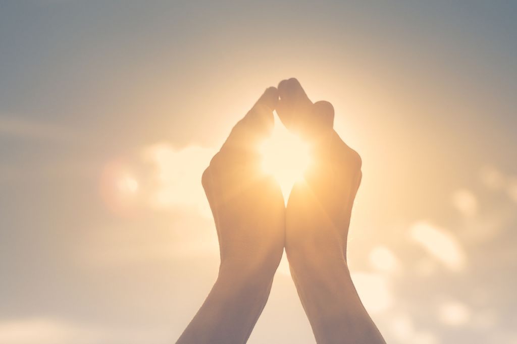 two hands cup the sun against the sky