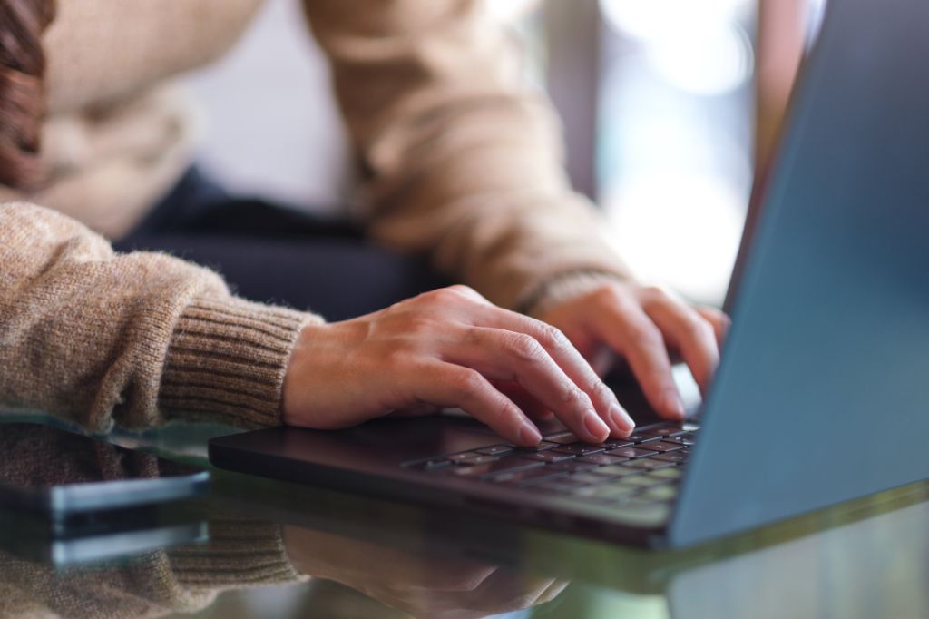 close up of woman's hands typing on laptop
