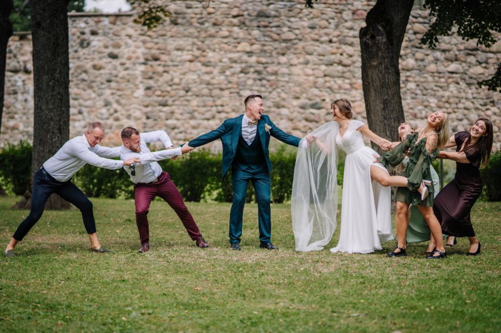 bride and groom at centre of tug of war, being pulled in opposite directions by family