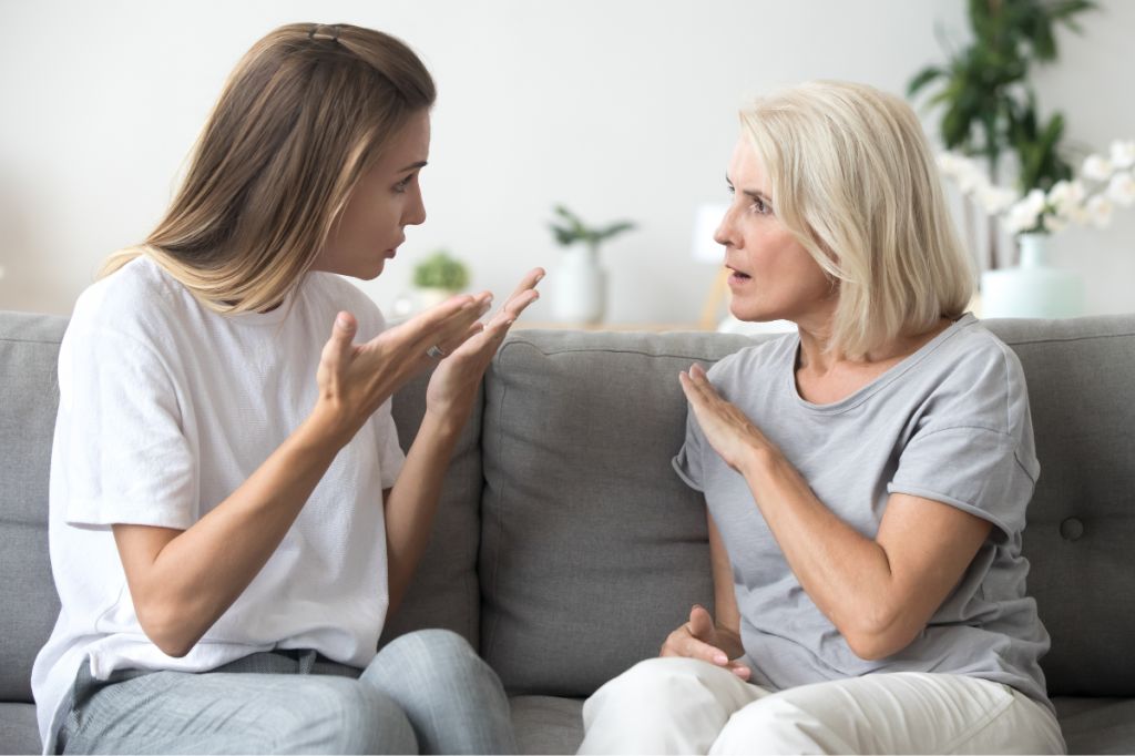 upset younger woman talks to mother asking her question, mother looks angry and upset