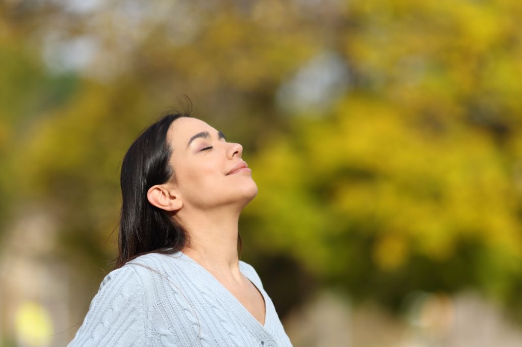 woman takes a deep breath in nature