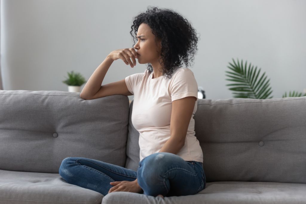 woman sits on sofa and looks upset