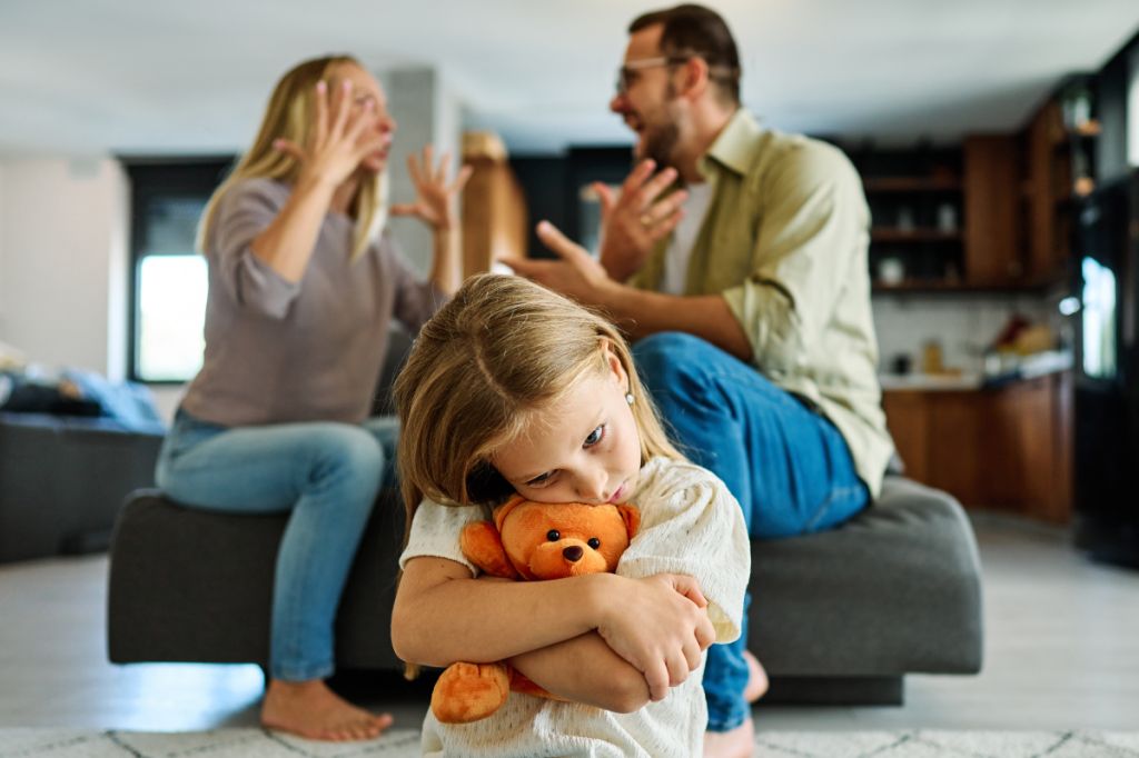 daughter upset and comforts herself as parents argue
