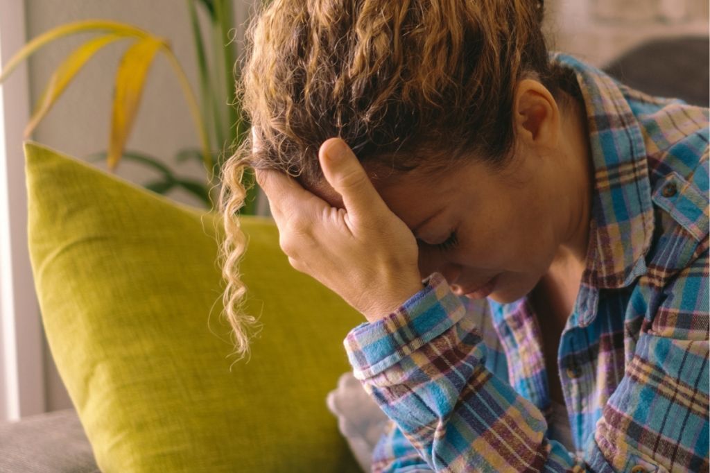 woman rests head in her hand, tired with the effort of holding things together
