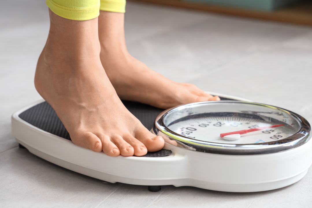 woman stands on weighing scales on tiptoe