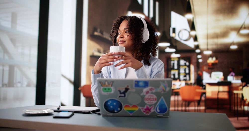 remote worker in a café coworking space, drinking coffee and working from her laptop