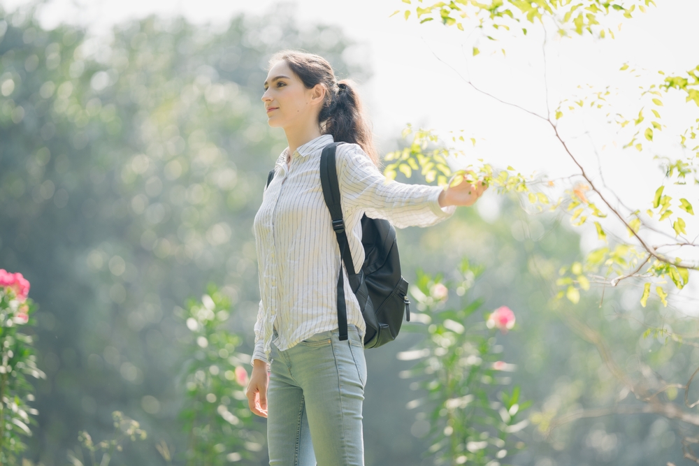 woman walking mindfully in nature wearing professional work clothes, mindful walking meditation to clear brain fog concept