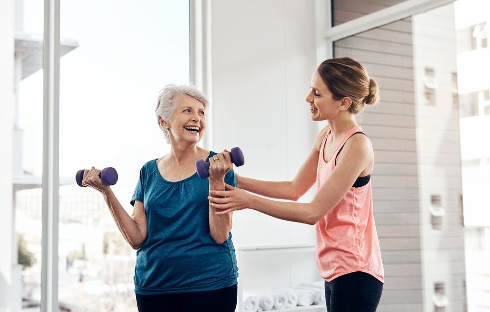 midlife senior woman exercising with physiotherapist personal trainer to improve chronic pain and stiffness