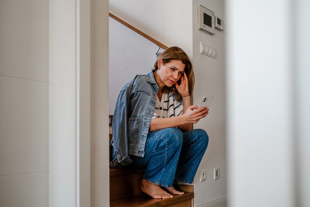 midlife woman looking tired and stressed as she checks her phone