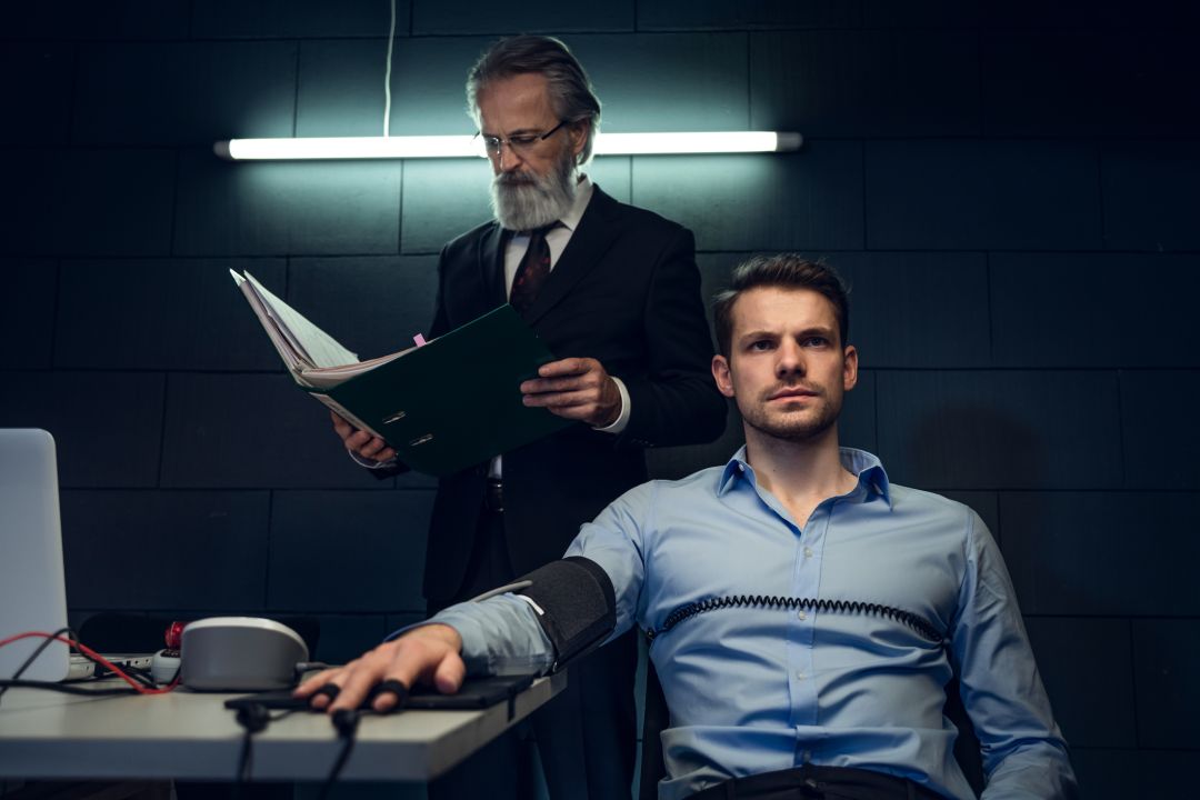 Arrested businessman having lie detector test in interrogation room