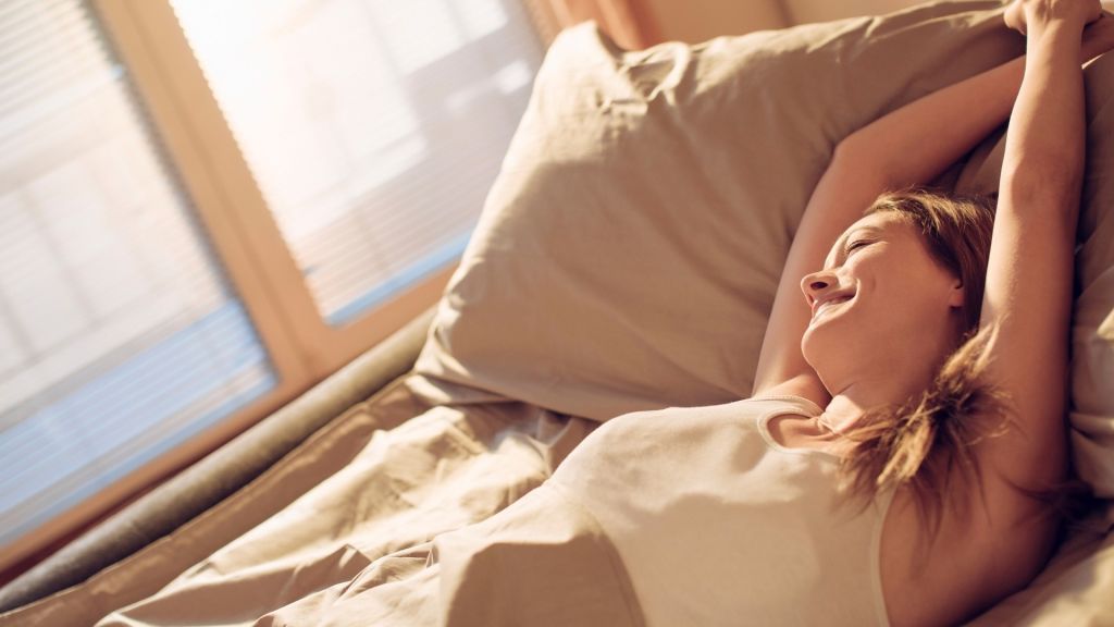 Woman stretching in bed, waking up with energy