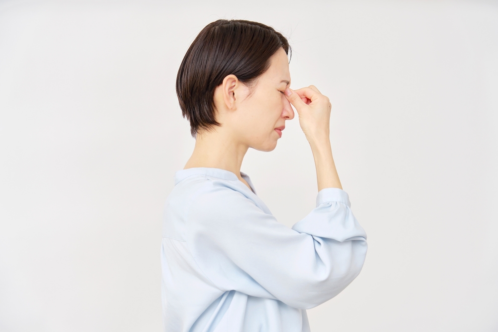 woman pinching between her eyebrows to ease a headache or brain fog