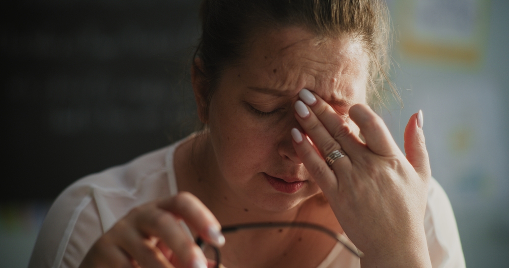 woman feeling stressed and upset, rubbing her tense forehead