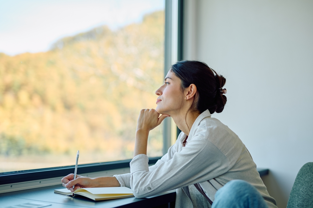 woman looking out of the window feeling hopeful while setting goals for the rest of the year