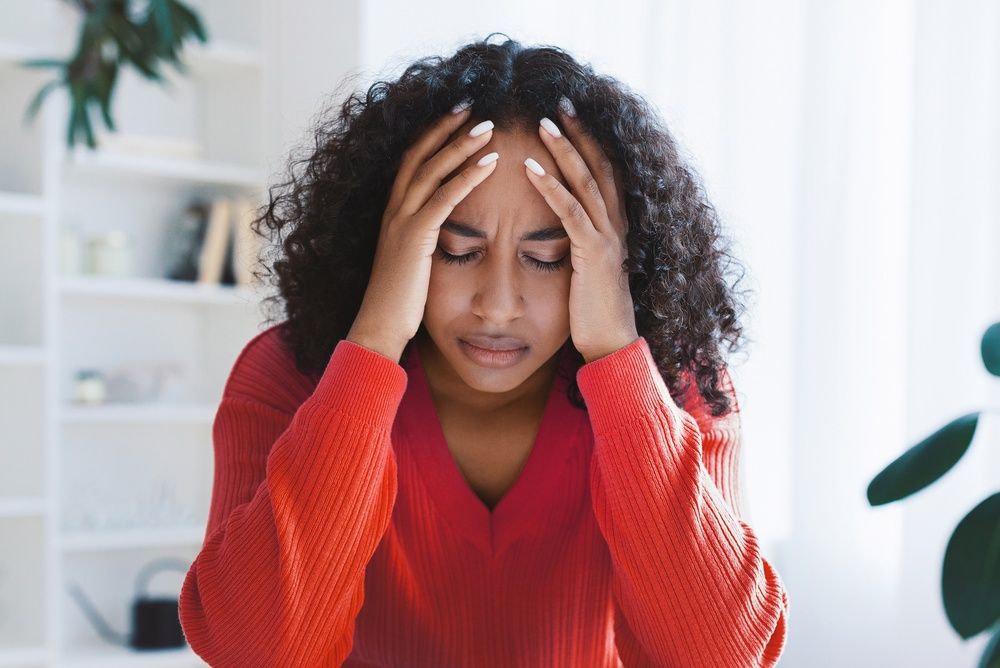 A woman in a red sweater with her head in her hands, looking upset